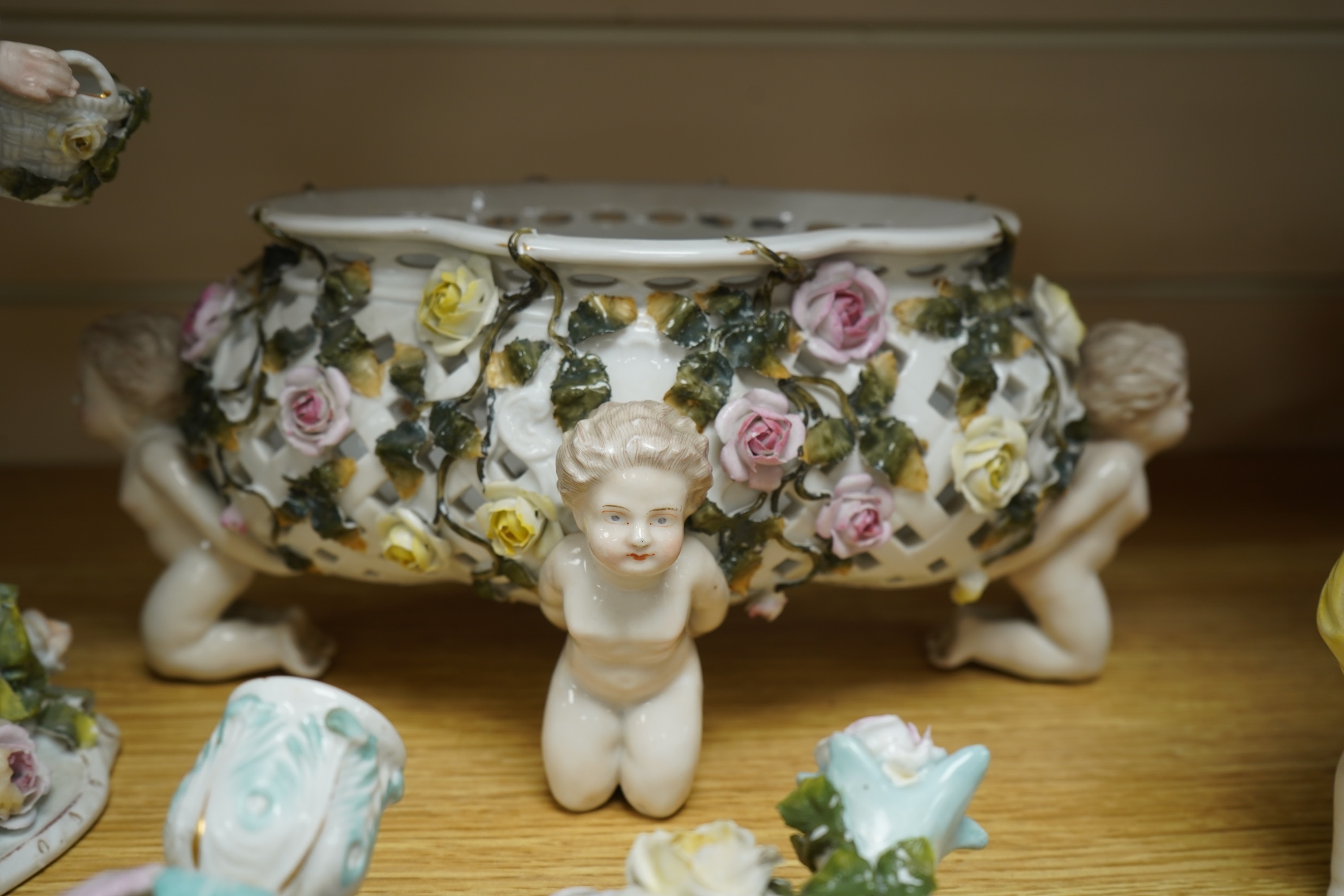 A German flower encrusted porcelain figural candelabrum, 30cm high, a cherub jardiniere and a cherub vase, all encrusted